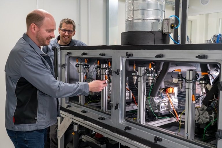 Kompressor-Prüfstand für R290 Zwei Mitarbeiter arbeiten an einem Kompressor-Prüfstand für R290