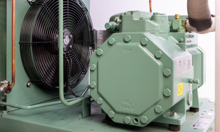 Foto eines Lüfters und Kompressors mit grün lackiertem Gehäuse aus einem Kältekreislauf.