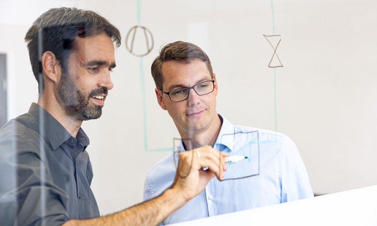 Kältekreislauf Skizze Ingenieur zeigt einem zweiten Ingenieur einen Kältekreislauf anhand einer Skizze.