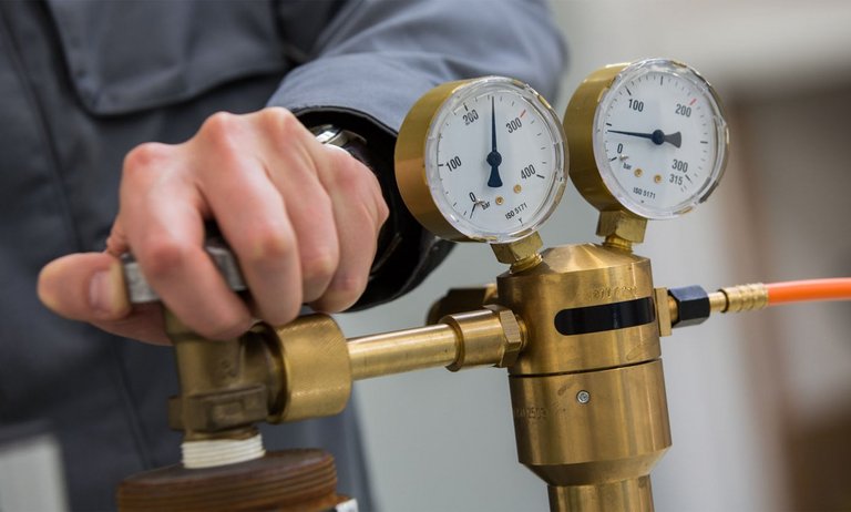 Close-up of Pressure Regulator Close-up of a pressure reducer. A person adjusts the valve. Gauges show gas pressure