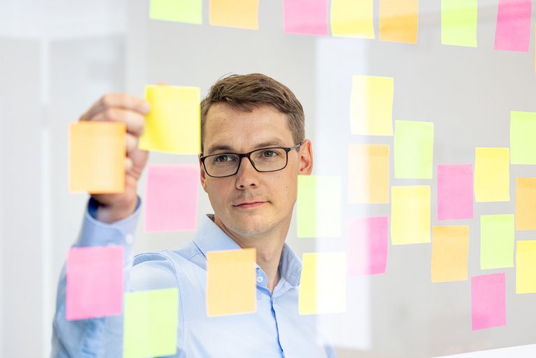 Employee with sticky notes An employee organizes notes on a glass wall